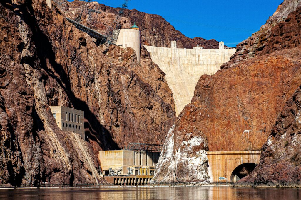 Stunning view of the Hoover Dam surrounded by rocky mountains under a bright blue sky.