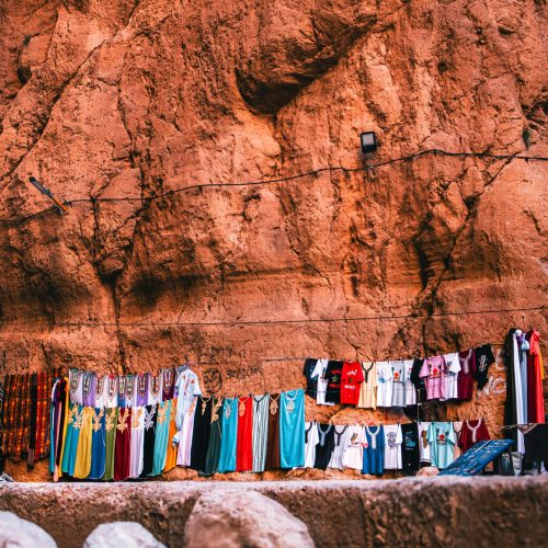 Vibrant Moroccan dresses hanging on a cliffside in Tinghir, Morocco, showcasing cultural beauty.